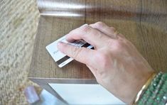 a person's hand holding a mouse on top of a wooden table with metal legs