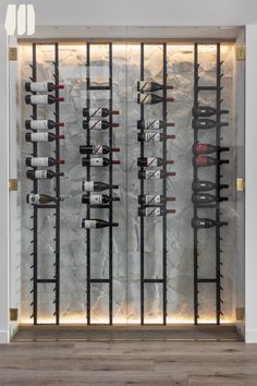 a wine rack with many bottles on it in front of a stone wall and wooden floor