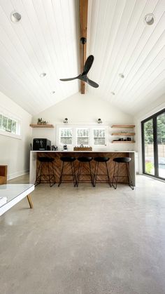 a large open room with a ceiling fan in it's center and two bar stools on the other side