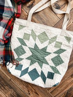 a quilted bag sitting on top of a wooden floor next to a plaid blanket