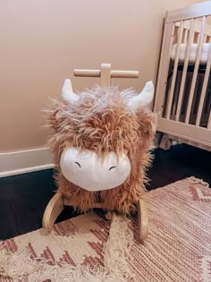 a stuffed animal sitting on top of a wooden rocking horse next to a crib