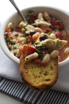 a white bowl filled with beans and vegetables on top of a blue and white napkin