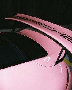 a pink sports car parked in a parking lot with its hood up and the word porsche written on it