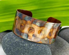 "Up for sale is this attractive one-of-a-kind flame painted copper metal cuff bracelet. You will receive the exact bracelet photographed in this listing. The color pattern is created entirely by 'painting' with the heat of a torch flame. No inks or paints were used in this design. The range of color produced by this process is absolutely amazing and will color shift depending on the light. The dominant colors on this bracelet are copper, red-orange and blues in a repeating circles pattern.  It was handmade by me in my jewelry studio located in Summerville, South Carolina.  The bracelet measures 1 inch wide by 6 inches long (when flat). The width across the wrist is approximately 2.5 inches. The opening is approximately 1.5 inches. This cuff bracelet is adjustable.  The best way to put on a Flame Painting, Playing With Fire, Fire Painting, Metal Cuff Bracelet, Hippie Bracelets, Copper Red, Jewelry Studio, Copper Metal, Circle Pattern