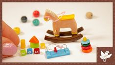 a hand holding a toy rocking horse surrounded by other toys and magnets on a white surface