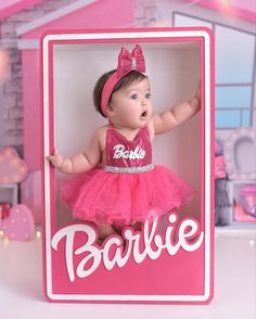 a baby doll in a pink dress with the word barbie on it's chest