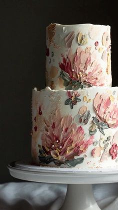 a three tiered cake decorated with flowers on a white platter in front of a black background