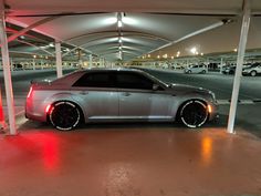 a silver car parked in an underground parking lot with red lights on the side of it