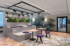 an office with plants on the wall and purple stools