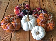 several pumpkins are arranged on a wooden floor with plaid fabric and twine handles