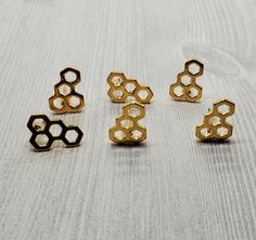 four pieces of gold metal sitting on top of a white cloth covered table next to each other