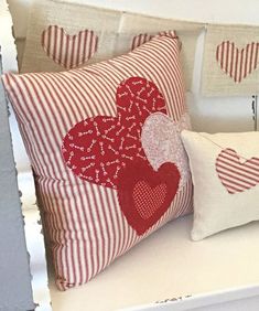 two red and white pillows sitting on top of a white shelf next to each other