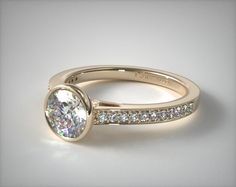 a close up view of a gold engagement ring with diamonds on the band and an oval shaped diamond in the center