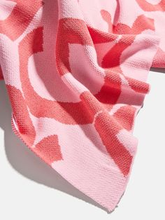 a pink and white scarf laying on top of a white surface with an orange pattern