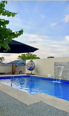 an empty swimming pool with a water feature in the middle and umbrellas over it