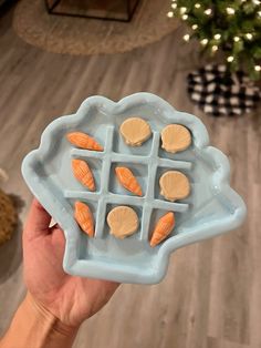 a person holding a blue plate with shell shaped cookies on it in front of a christmas tree