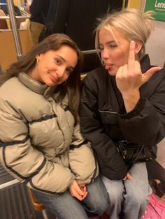 two women sitting next to each other on a bus giving the peace sign with their fingers