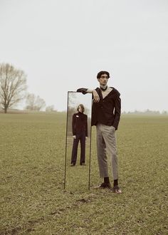 a man standing next to a mirror in a field