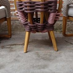 a wooden table topped with lots of chairs next to a brick wall and cement floor