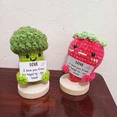 two small crocheted fruits sitting on top of a wooden table next to each other