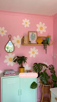 a pink room with flowers painted on the wall and plants in pots next to it