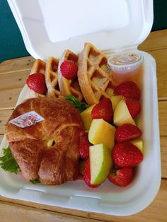 a plastic container filled with fruit and waffles