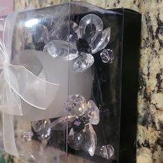 a clear box with some crystal stones in it and a bow on the front side