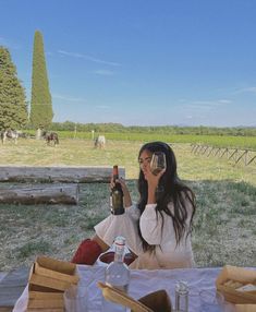 a woman sitting at a table with a bottle of wine in front of her face