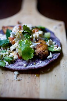 a tortilla filled with lots of toppings on top of a wooden cutting board