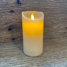 a lit candle sitting on top of a wooden table next to a wood plank wall