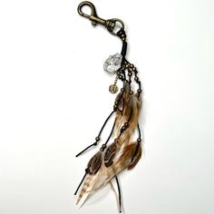 a piece of jewelry with feathers hanging from it's hooks on a white background