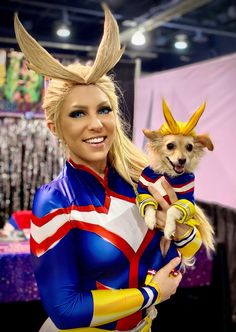 a woman holding a small dog in her arms while standing next to a table with decorations on it