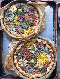 two pies with flowers painted on them sitting on top of a pan