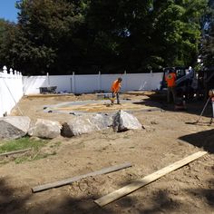 two men are working on the construction of a house in the yard with large rocks