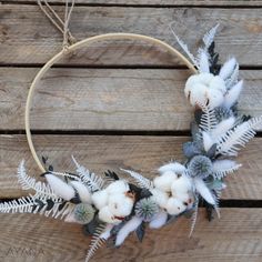 a wreath with white flowers and green leaves on a wooden surface, hanging from a hoop