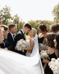 the bride and groom are surrounded by their bridal party friends at this outdoor wedding