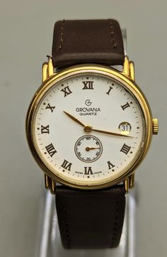 GROVANNA men's quartz watch featuring a white dial with raised gold hour markers and hands with a seconds sub-dial and a date window on a new brown leather two-piece strap. New battery running well. 31.5mm case size Classic Brown Watch Accessories With Date Indicator, Formal Brown Watches With Date Display, Brown Watches With Date Display, Formal Brown Watch With Date Display, Men Pants Pattern, Brown Watch, Gold Watch Men, Mens Luxury, Philadelphia Pa