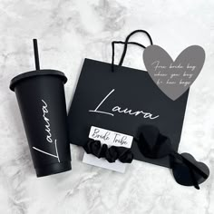 a black paper bag, coffee cup and sunglasses on a marble surface with the name laura written on it