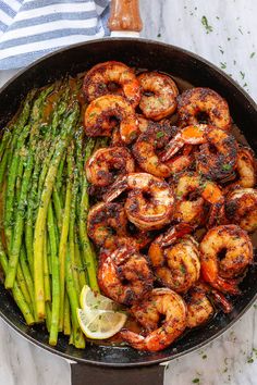 shrimp and asparagus in a skillet with lemon wedges on the side