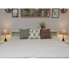 a bed with two lamps on either side and pictures above the headboard in front of it