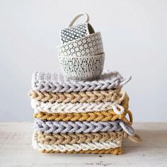 a stack of crocheted blankets with a cup on top of one and another mug in the middle