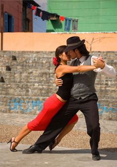 a man and woman are dancing in the street with their arms wrapped around each other