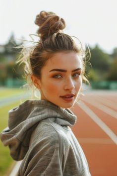 Person with hair in a top bun, wearing a hoodie, standing on a running track looking back. Best Hairstyles For Running, Hairstyles For Running Workouts, Running Ponytail Hairstyles, Hairstyles For Running, Long Hair Running Hairstyles, Running Hair, Running Late Hairstyles, Running Hairstyles