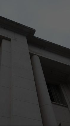 a clock on the side of a tall building with columns and a sky in the background