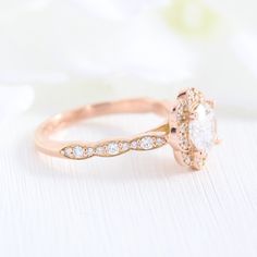 a close up view of a diamond ring on a white surface with flowers in the background