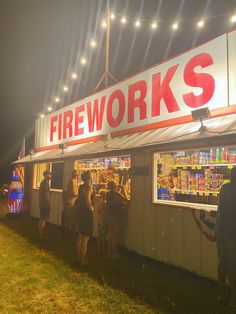 people are standing in line to get food from the fire works stand at night time