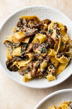 two white bowls filled with pasta and mushrooms