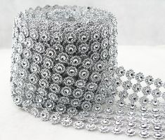 a roll of silver sequinized ribbon on a white surface with two rows of beads