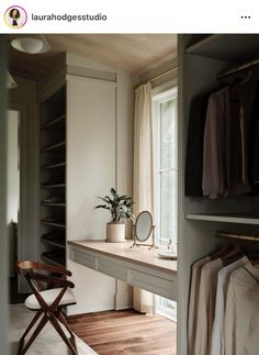 an open closet with clothes on hangers and a chair in front of the window