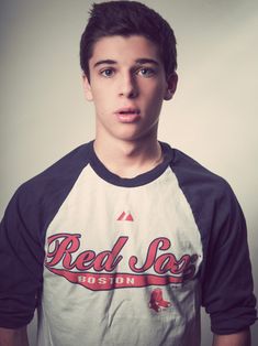 a young man in a baseball shirt making a funny face with his hand on his hip